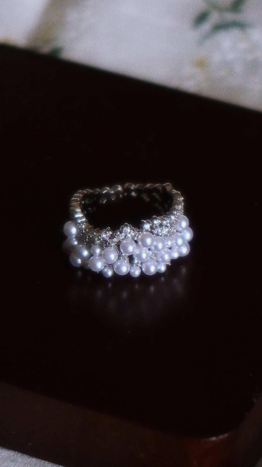 Pearl and crystal ring on a dark surface