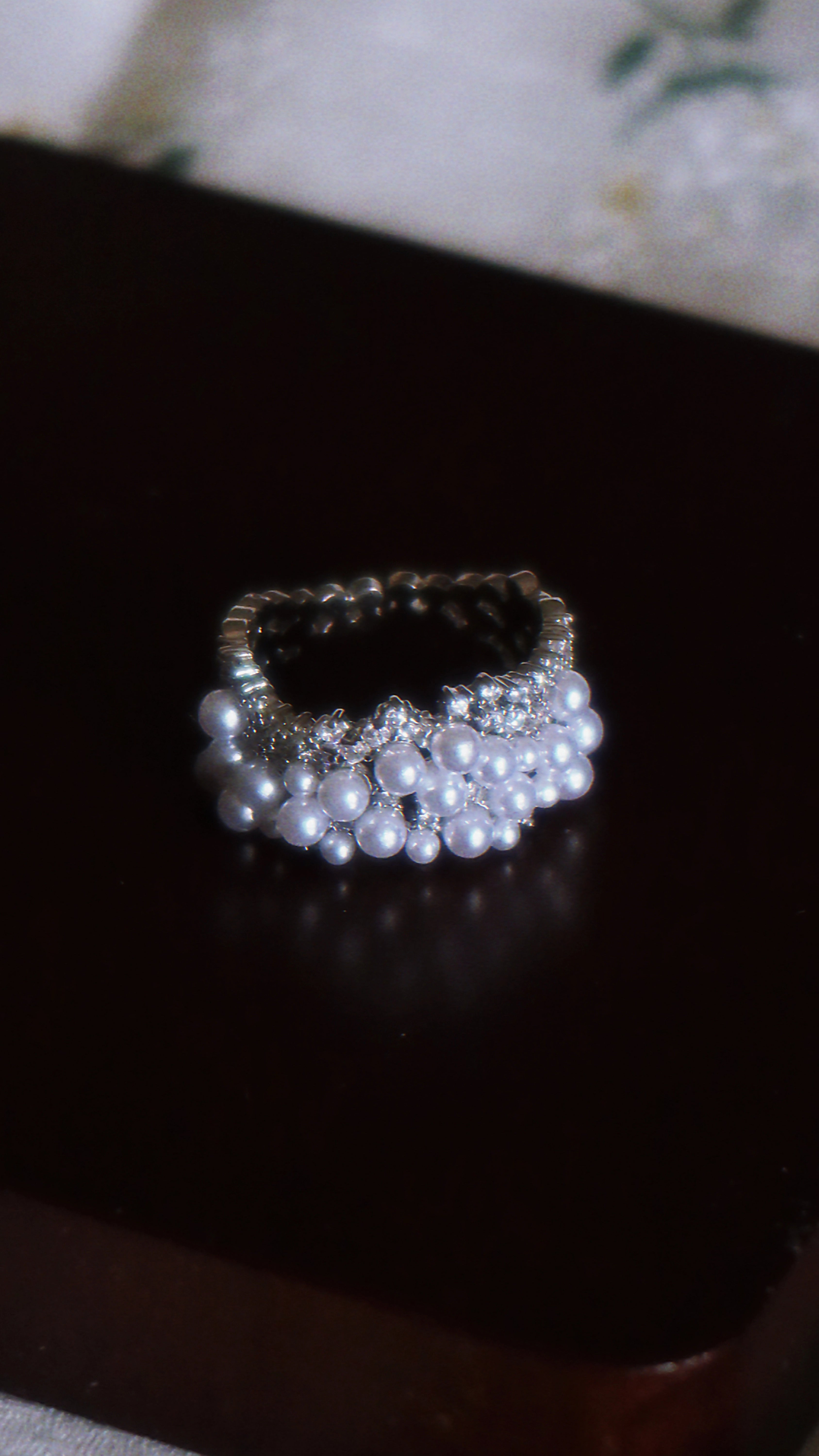Pearl and crystal ring on a dark surface