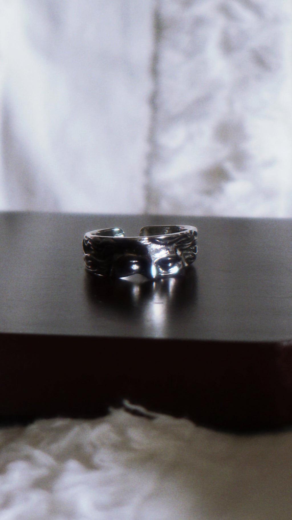 Silver ring on a dark surface with a blurred white background