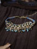 The Peacock's Muse antique green hand-woven bracelet, showcasing a structured row of green glass beads, natural tiger's eye, and micro-paved green zircons on a dark wrinkled textured fabric.