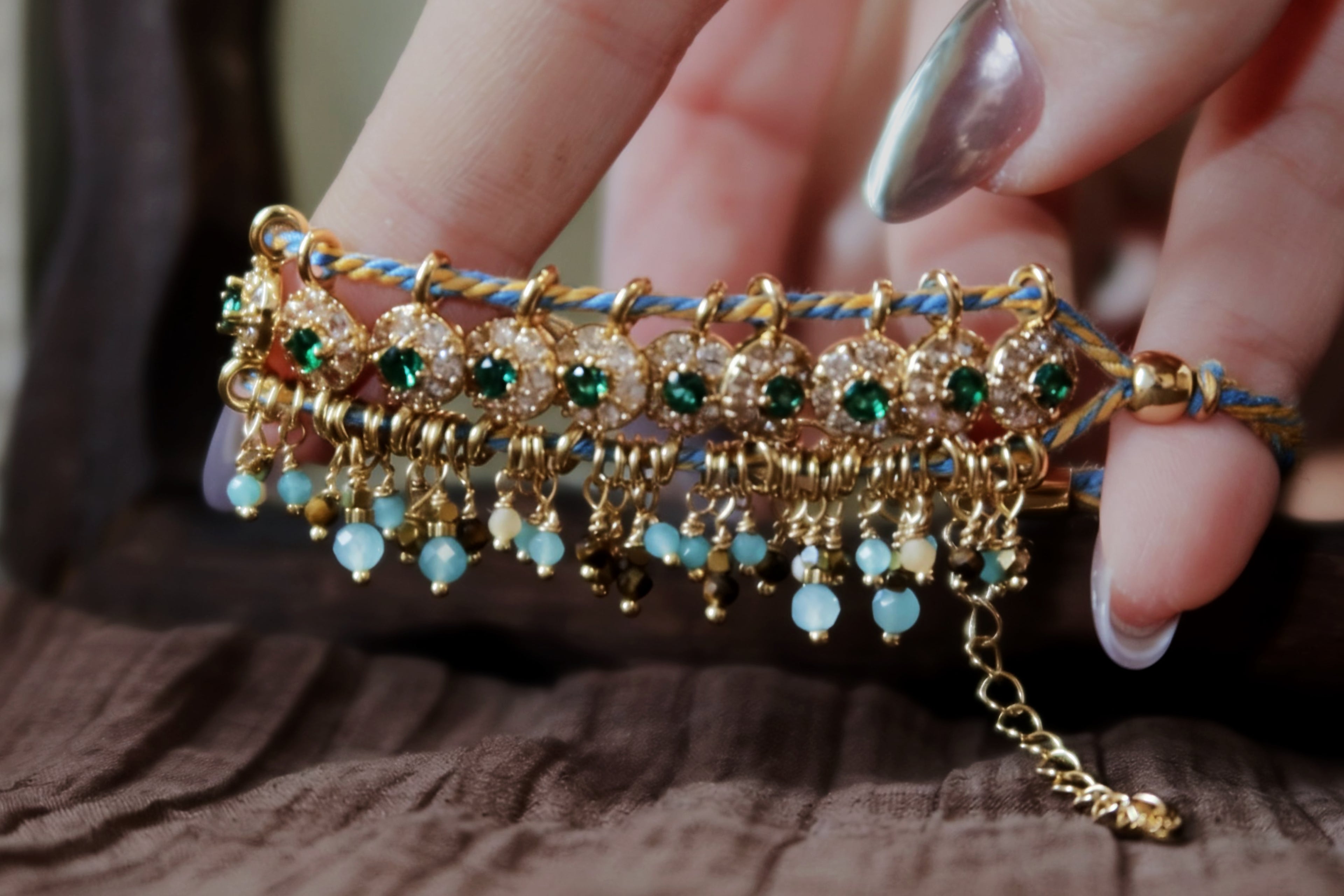 Close-up detail of the Peacock's Muse antique green hand-woven bracelet, focusing on the meticulous handcrafted braided cords, glowing green glass beads, and natural tiger's eye chatoyancy.