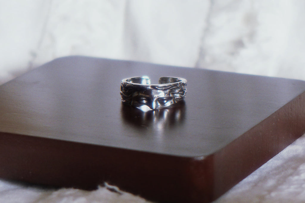 Silver ring on a dark wooden surface with a blurred background