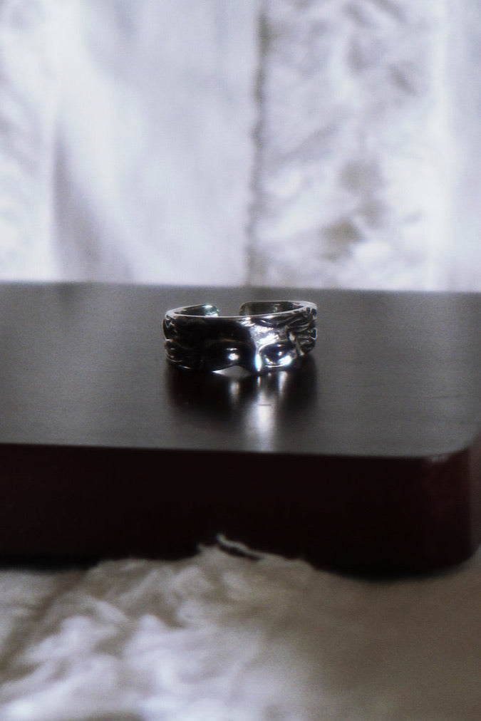 Silver ring on a dark surface with a blurred white background
