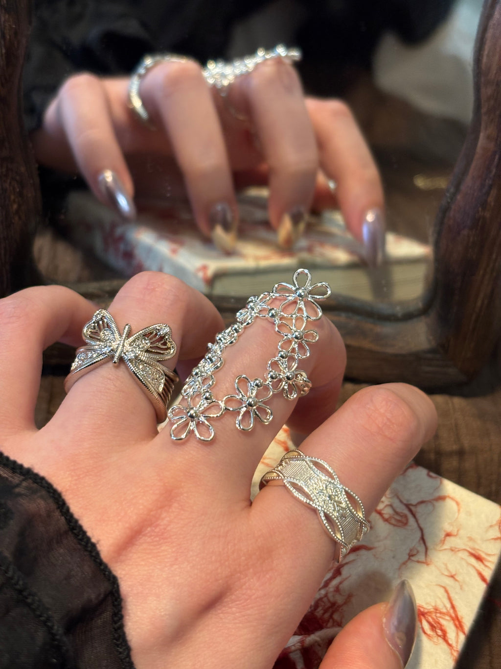 A curated silver ring stack featuring the Interwoven Blooms oval filigree ring as a stacking centerpiece, paired with butterfly rings and minimal midi bands for a relaxed French romantic layered look.