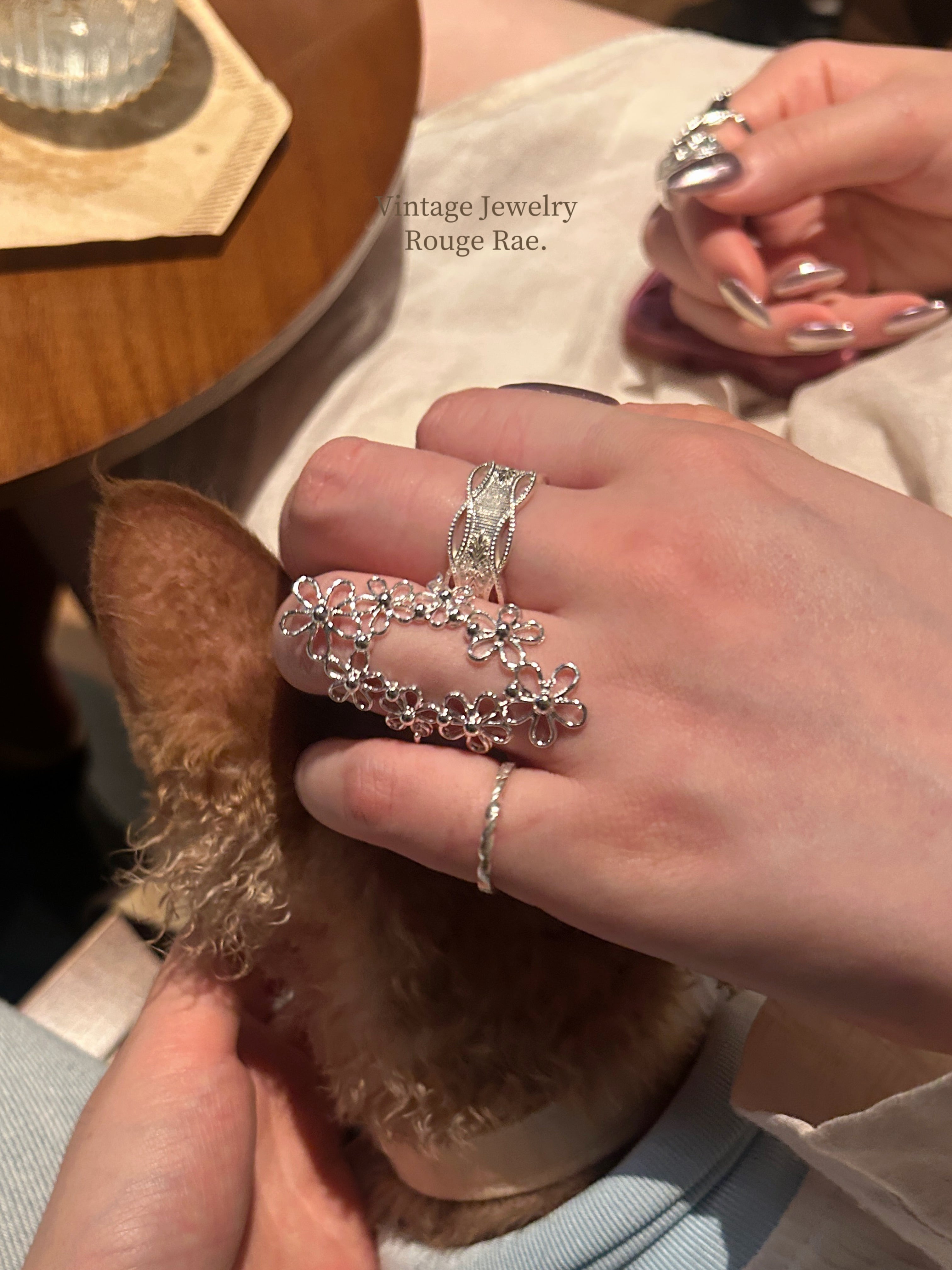 On-model view of the Interwoven Blooms oval filigree statement ring worn on a finger, naturally elongating and flattering the hand shape with its French vintage lace flower design.