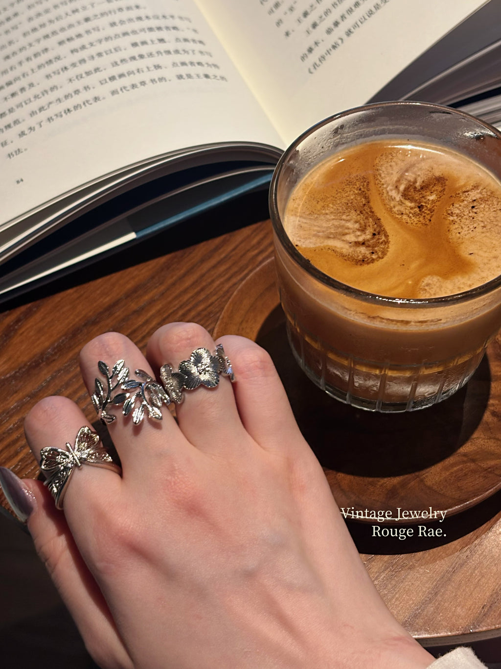 Laurel leaf ring stacked with butterfly and floral rings on hand